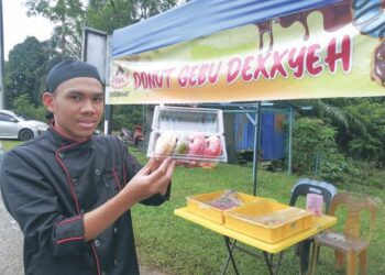 MUHAMMAD Farish Ikhwan Abd. Razak menunjukkan donut yang dijualnya di Kampung Menerong, Ajil, Hulu Terengganu. - UTUSAN/NOOR HAYATI MAMAT