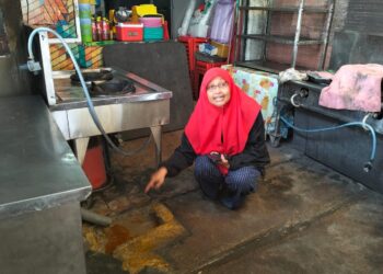 SEORANG peniaga menunjukkan keadaan longkang yang tersumbat 
di medan selera Batu Buruk, Kuala Terengganu, Terengganu. – UTUSAN/KAMALIZA KAMARUDDIN