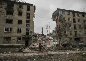 PENDUDUK menunggang basikal melepasi sebuah bangunan pangsapuri yang musnah akibat serangan Russia di bandar Avdiivka, Donetsk Oblast. - AFP   