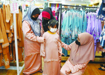 NOR Balqis Batrisya Razak (kanan) dan tiga adiknya mencuba pakaian raya dalam Program Kasih Ramadan EPIC Bersama Anak Yatim di Kuala Nerus, semalam. - UTUSAN/PUQTRA HAIRRY ROSLI