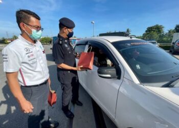 MOHD. Mahiri Hussin menyampaikan cenderahati kepada pengguna jalan raya pada program Jelajah Op Selamat 18 PDRM Bersama Petronas sempena sambutan Hari Raya Aidilfitri di Stesen Petronas Anak Bukit di Alor Setar, hari ini. - UTUSAN/JAMLIAH ABDULLAH