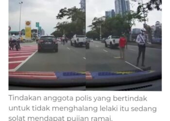 TANGKAP  layar video tular anggota polis trafik mengawal lalulintas berikutan terdapat individu solat di tengah-tengah jalan raya. -GAMBAR MEDIA SOSIAL
