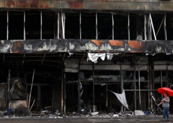 PENDUDUK berjalan melepasi sebuah pusat beli-belah yang musnah di Bucha, wilayah Kyiv, Ukraine. - AFP