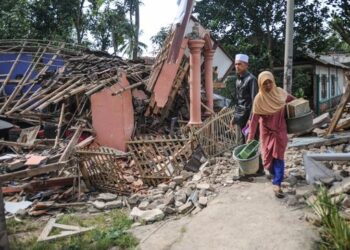 PENDUDUK melihat serpihan bangunan yang rosak teruk akibat gempa bumi di Cianjur di Jawa Barat Isnin lalu.-AGENSI