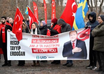 PENUNJUK perasaan memegang bendera Turkiye dan sepanduk menyokong Erdogan semasa demonstrasi di luar Kedutaan Turkiye di Stockholm, Sweden.-AFP