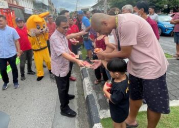 MOHD. Shafie Apdal mengagihkan angpau kepada orang ramai di Tanjung Aru, Kota Kinabalu hari ini.