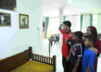 NOORAZIAH Noor melihat potret gambar Allahyarham Asisten Superintenden Zulkifli Mamat yang digantung di dinding kediaman mereka di Kangar, Perlis, sambil ketiga-tiga anaknya memberikan tabik hormat. 
– UTUSAN/IZLIZAN OTHMAN