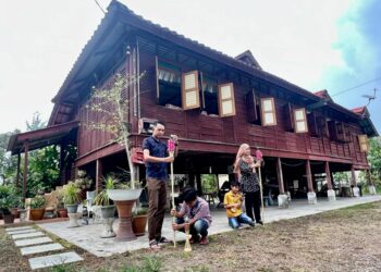 LAKSAMANA Saad (kiri) bersama ahli keluarganya menghiasi rumah pusaka diwarisi mereka di Kampung Abi Tengah, Kangar, Perlis bagi menyambut ketibaan saudara-mara semasa Aidilfitri. – UTUSAN/ASYRAF MUHAMMAD
