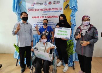 Nadzerah Abdullah (kanan) bersama Johnny (kiri) bergambar bersama penerima vaksin pada Program Outreach Vaksinasi Covid-19 di Papar hari ini