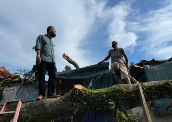 WAN Hassan (kiri) meninjau kerosakan atap rumah Wan Mohamed Khozani di Kampung Sungai Petai, Pasir Puteh. - UTUSAN/TOREK SULONG