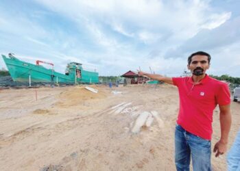 MURKHAN Jasin menunjukkan bot yang sempat diselamatkan dalam kejadian arus deras di Terusan Semerak, Tok Bali, Pasir Puteh, Kelantan. -UTUSAN/TOREK SULONG