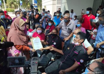 Siti Zailah Mohd. Yusoff (kiri) menerima memorandum yang diserahkan oleh gabungan persatuan OKU di pekarangan bangunan Kementerian Pembangunan Wanita, Keluarga dan Masyarakat, Putrajaya.