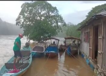 PENDUDUK sedang menambat beberapa buah bot penambang pada tiang rumah berikutan air melimpah masuk ke kawasan kediaman dan dataran kedai kopi di pesisir Sungai Tembeling di Kampung Bantal dinJerantut, Pahang. - FOTO/ IHSAN PENDUDUK KAMPUNG BANTAL