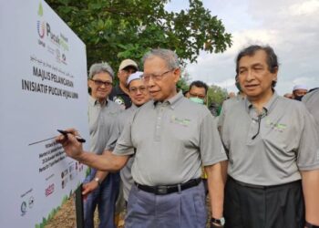 MUSTAPA Mohamed (depan) menandatangani papan tanda Majlis Pelancaran Inisiatif Pucuk Hijau UMW di Pantai Sri Tujoh, Tumpat hari ini/ FOTO:ROSALWANI CHE SOH