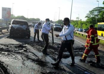 ANGGOTA trafik membersihkan jalan yang berminyak berikutan kemalangan jalan raya melibatkan empat kenderaan termasuk sebuah kereta BMW rentung dan menyebabkan pemandunya maut di Jalan Persisiran Pantai, Bakar Batu-Permas Jaya, Johor Bahru semalam. – UTUSAN/RAJA JAAFAR ALI
