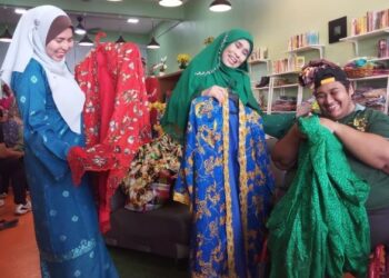 KARTINA Aziz (tengah) bersama Natipah Abu (kiri) dan Ahmad Zarrin Anas Ahmad Kamal yang berkerusi roda memegang baju-baju kebaya Mami Jarum di Butik Qasehku.com di Taman Ria, Sungai Petani.