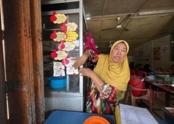 ENDON Salleh menunjukkan senarai harga makanan yang tertera di kedai makannya untuk rujukan pelanggan. – UTUSAN/KAMALIZA KAMARUDDIN