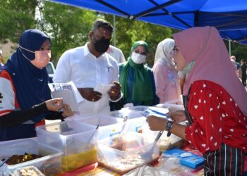 J. Arul Kumar (dua dari kiri) bersama Siti Yusnita (kiri) mengedarkan risalah kepada peniaga di Bazar Ramadan Bandar Baru Nilai, Seremban hari ini.- UTUSAN/ZAKKINA WATI AHMAD TARMIZI