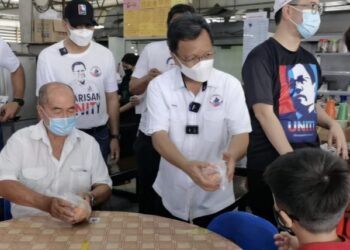 MOHD. Shafie Apdal (tengah) mengagihkan limau mandarin kepada orang ramai di Pekan Inanam, Kota Kinabalu hari ini.