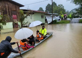Anggota polis membantu mangsa banjir di Kampung Chenulang, Kuala Krai hari ini. - Ihsan POLIS