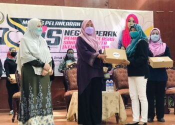 WAN Norashikin Wan Noordin (tengah) menyerahkan kotak PROKiS kepada penduduk pada program di Ipoh, hari ini. UTUSAN/LIYANA RAMLI