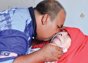 ROSLI Itam mencium pipi Rusmahwati Wazir Mohamed yang koma selama 18 tahun dan terlantar sejak 2004 di rumah mereka di Taman Sri Mahkota Aman, Kuantan, Pahang. - UTUSAN/SHAIKH AHMAD RAZIF