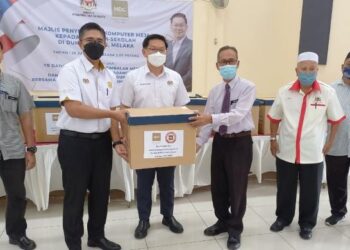 LIM Ban Hong (tiga dari kiri) menyerahkan komputer meja pada majlis penyerahan kepada sekolah-sekolah dalam DUN Klebang, Melaka. - UTUSAN/AMRAN MULUP