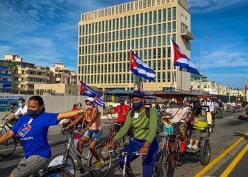 ORANG ramai mengibarkan bendera Cuba semasa mengambil bahagian dalam perarakan anjuran Kesatuan Komunis Muda melintasi bangunan Kedutaan AS di Havana. - AFP