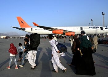 PENDUDUK Afghanistan berjalan menuju ke pesawat di Lapangan Terbang Antarabangsa Hamid Karzai, Kabul. - AFP