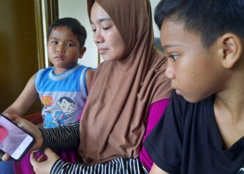 NURUL Wahida Jamaluddin bersama anaknya, Muhamad Syahmi Nakha'ie (kanan) dan Muhamad Syafi Naquiddin melihat gambar kesan luka di belakang badannya yang masih belum sembuh ketika ditemui di Kampung Sungai Badak, Kulim, Kedah. -UTUSAN/AZAHAR HASHIM