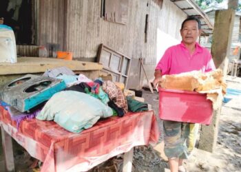 SHAARI Che Noh membawa keluar barangan yang rosak selepas rumahnya ditenggelami banjir di Kampung Serongga, Pasir Mas, Kelantan. - UTUSAN/ROHANA ISMAIL