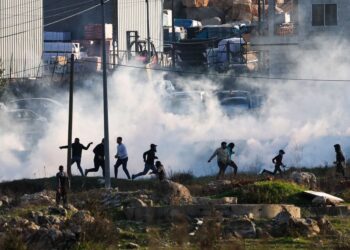 PENDUDUK Palestin membaling batu ke arah jentolak tentera Israel sewaktu konfrontasi di bandar Jenin, Tebing Barat, kelmarin. -AFP