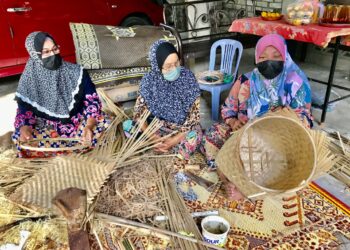 NURIZAN Hamzah (kanan) bersama rakan-rakan menganyam bakul yang ditempah pelanggan di Kampung Jal Kechik, Tumpat. - UTUSAN/ROSLIZA MOHAMED