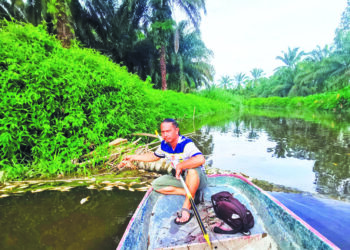 SAIFUL Azam Mohd. Sapari menunjukkan ikan yang mati dipercayai akibat pencemaran air Sungai Labu di Chikus dekat Pasir Salak baru-baru ini. – UTUSAN/AIN SAFRE BIDIN
