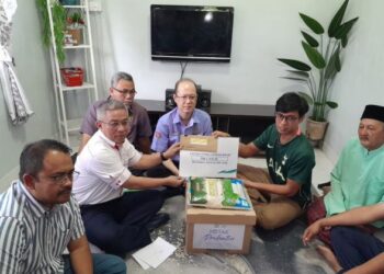 ADHAM BABA (dua dari kiri) menyerahkan faedah pencen penakat Perkeso kepada Muhammad Redzuan di Kampung Batu 4, Kota Tinggi.