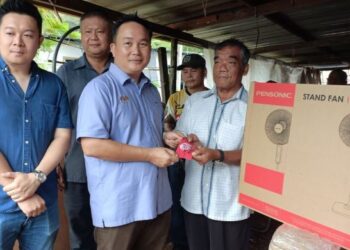 WILLIE (tengah) menyerahkan bantuan sumbangan Persatuan Industri Perabot Sarawak kepada Jugah Ganjoh (kanan).