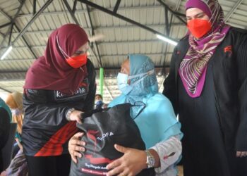 Noor Razlina (kiri) menyampaikan sumbangan bakul makanan kepada salah seorang penerima di Taman Sri Rugading, Telipok di Kota Kinabalu semalam.