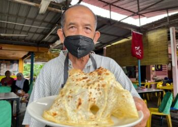 WAN Hassan Wan Omar menunjukkan roti canai surat khabar yang laris dijual di kedainya di Bandar Baru, Gua Musang, Kelantan. - UTUSAN/AIMUNI TUAN LAH