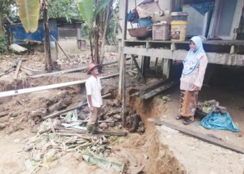 TUAN Dahlan Tuan Endut dan Cheku Fatimah Cheku Yatim melihat kesan hakisan tanah di belakang rumah mereka di Kampung Lubuk Erong, Hulu Terengganu, Terengganu. - UTUSAN/NOOR HAYATI MAMAT