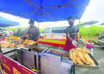 AZIMI Abdul Razak (kanan) menjual ayam gunting di Pekan Sehari Jerantut di Jerantut, Pahang dengan harga RM8 sekeping walaupun harga ayam dan barangan semakin meningkat. - UTUSAN/NORHAFIZAN ZULKIFLI