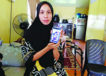 YAWARE Samoh menunjukkan gambar anak tunggalnya yang maut dipercayai terkena serangan strok haba di rumahnya di Kampung Kota, Kota Bharu, Kelantan. – UTUSAN/ROHANA MOHD.NAWI