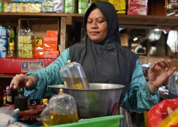 SEORANG penjual menimbang satu beg minyak masak di pasar tradisional di Jakarta.-AFP