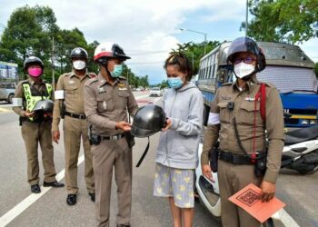 POLIS di wilayah Trat memberi topi keledar percuma kepada penunggang motosikal yang ditahan. - NAEWNA