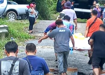 Anggota polis dan penduduk kampung membawa keluar mayat mangsa dari tempat kejadian.
