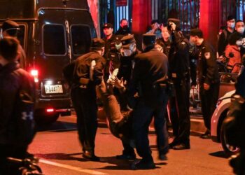 SEORANG lelaki ditahan ketika orang ramai berkumpul di jalan di Shanghai kelmarin.-AFP