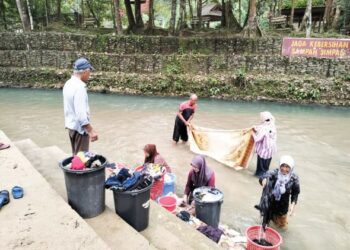 PENDUDUK membasuh pakaian di sungai selepas bekalan air di rumah mereka masih terputus di Kampung La, Besut, Terengganu. - UTUSAN/KAMALIZA KAMARUDDIN