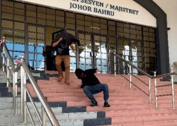 Wan Kamarul Za'im Wan Mansor terjatuh ketika cuba melarikan diri bersama Amir Izham Shahak (kiri) daripada jurugambar setelah didakwa atas tuduhan menipu untuk menerima wang di Mahkamah Sesyen, Johor Bahru di Johor. -UTUSAN/RAJA JAAFAR ALI