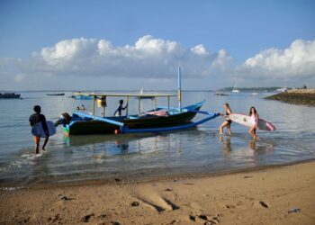 PELANCONG asing ingin melakukan aktiviti meluncur ombak di Sanur, Bali. - AFP