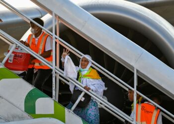 SEORANG jemaah haji wanita melambai ke arah keluarganya ketika menaiki pesawat menuju ke Mekah di lapangan terbang di Aceh, baru-baru ini. - AFP