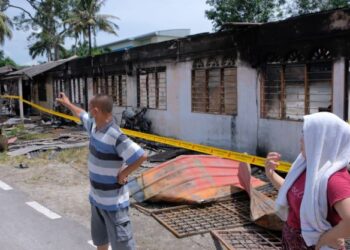 BEBERAPA orang jiran yang tinggal di rumah sewa bertentangan menunjukkan keadaan deretan rumah yang telah musnah dalam kejadian kebakaran di Kampung Jenderam Hilir, Dengkil, Selangor. - UTUSAN/KAMARIAH KHALIDI